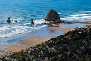 Haystack Rock in Cannon Beach Oregon on a sunny day with the town in the foreground. 