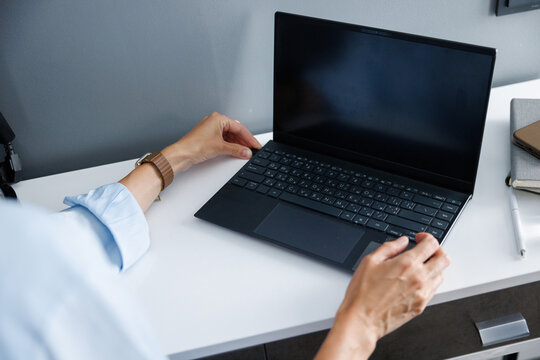 Partial of businesswoman insert flash card in laptop on nightstand
