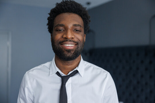 Portrait of partial young smiling black businessman looking at camera