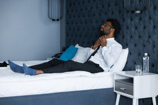 Young black entrepreneur loosen one's tie lying on comfortable bed