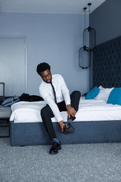 Front view of black businessman or entrepreneur takeoff shoe on bed