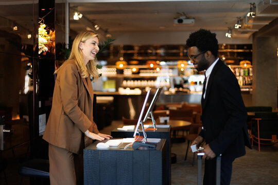 Laughing receptionist and entrepreneur with suitcase in hotel lobby