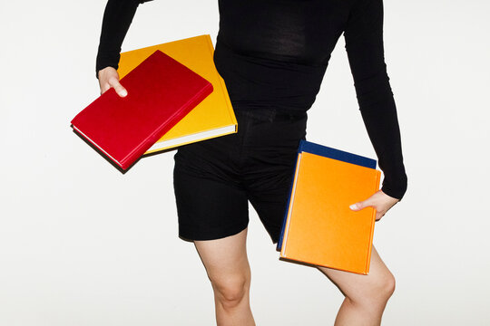 Person wearing fashion outfit & holding colourful puplication books 
