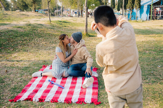 Boy Photographs Couple Kissing Outdoors 