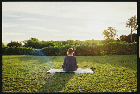 Woman doing yoga at sunrise on a lawn