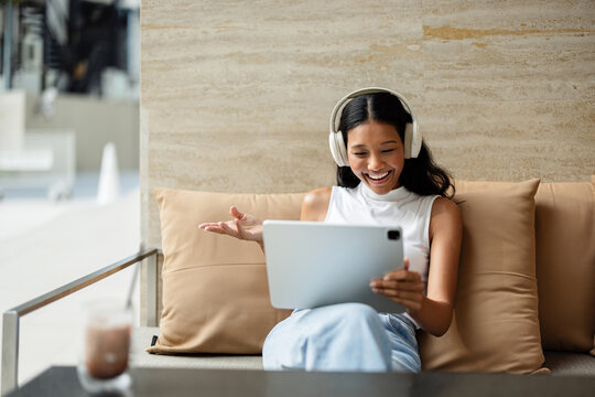 Happy Woman With Headphones Having a Video Call on a Tablet