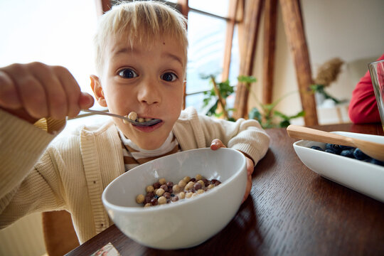 The little boy eats cereals for breakfast