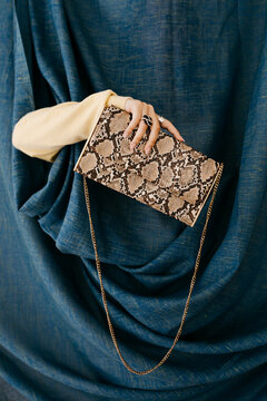 Hand with rings holding snakeskin clutch bag 