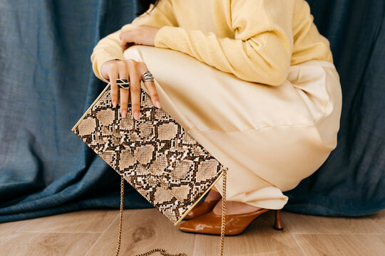 Woman holding snakeskin clutch handbag 