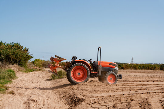 Orange Tractor Plowing Farmland