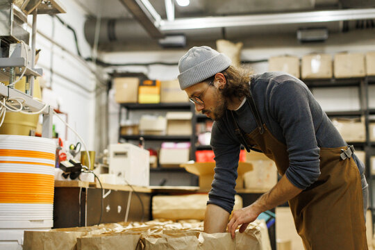 Male worker preparing packages with coffee beans for distribution