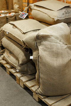 Collection of sacks with coffee beans on wooden pallet at warehouse