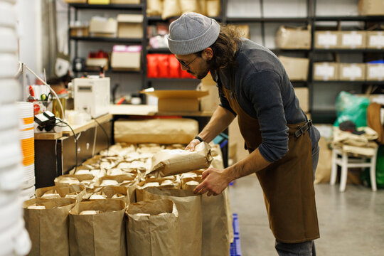 Side of male worker preparing or checking packages with coffee beans