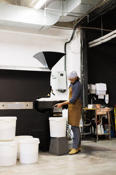 Man controlling of coffee beans falling out in bucket from machine