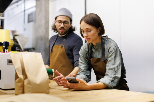 Focused female worker watching digital tablet near male colleague