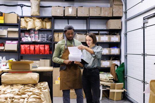 Workers watching list on clipboard at warehouse of coffee factory