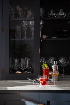 Dresser containing stemware with mixed drinks and a cocktail shaker.