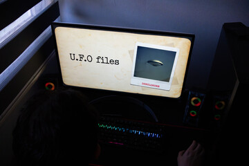 UFO Files Graphic with Flying Saucer Photo and Disclosure Stamp on Monitor, Conceptual Scene of Late Night Research into Extraterrestrial Secret Files