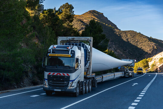 Special transport truck carrying an oversized wind turbine blade on a rural road