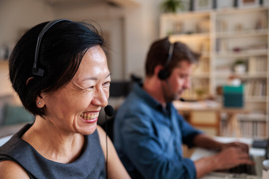 Two people wearing headsets working at their computers.