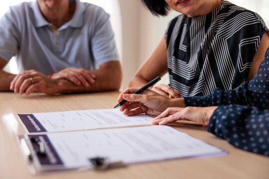 Couple signing documents with advisor at table.