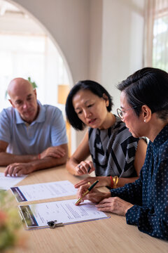 Couple signs real estate purchase agreement with agent.