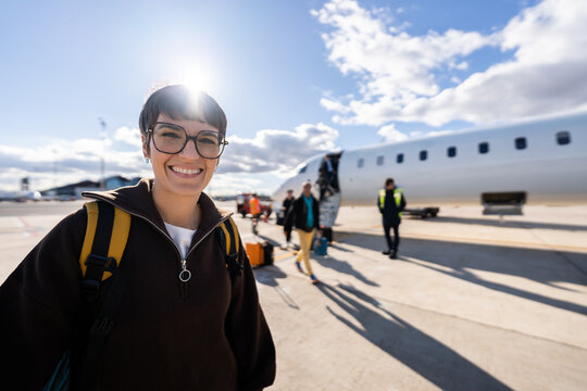 Young woman confidently smiling at airport before boarding airplane