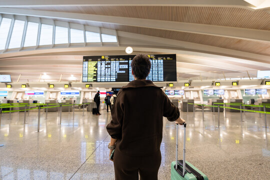 Woman with luggage checking airport departure board