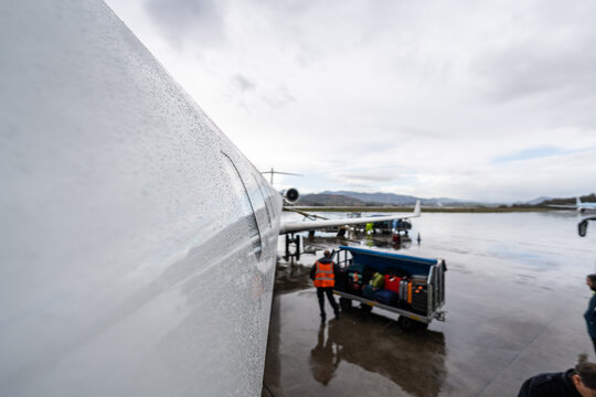Airplane fuselage covered in raindrops on airport tarmac