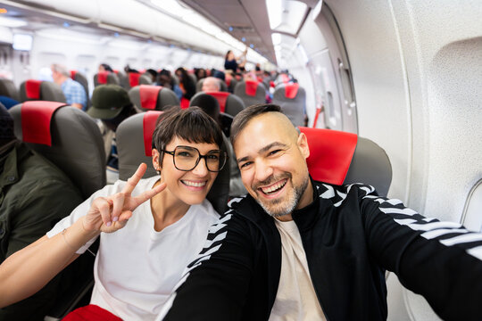 Happy couple taking selfie enjoying airplane travel