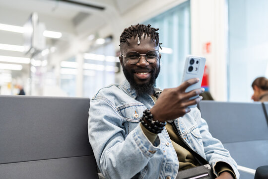 Young man communicating on smartphone in airport lounge