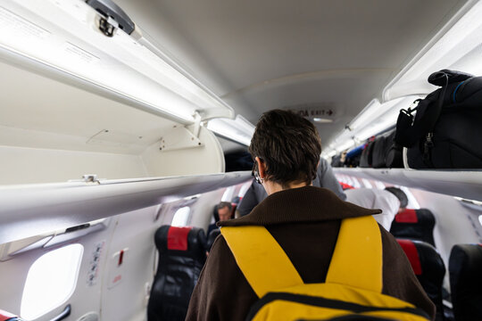 Passenger boarding airplane storing luggage in overhead bin