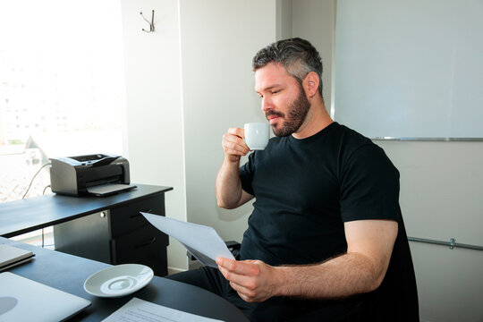 Man Reviewing Documents with Coffee at the Office