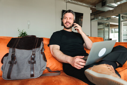 Man Calling While Working on Laptop in Lounge