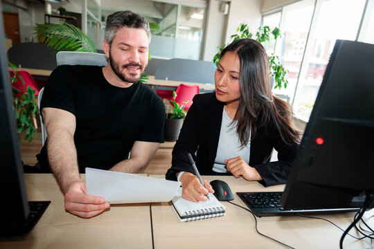 Colleagues Discussing Work and Taking Notes at Desk