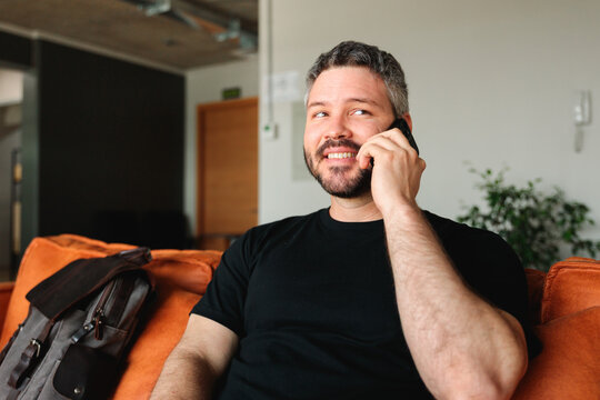 Smiling Man Taking a Phone Call in Coworking Lounge