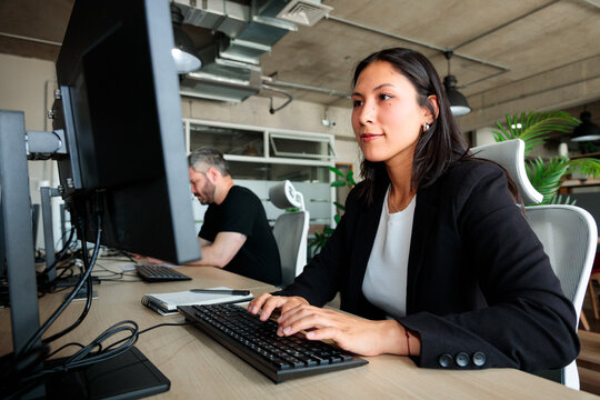 Focused Latina Woman Working at Desk in Coworking Office