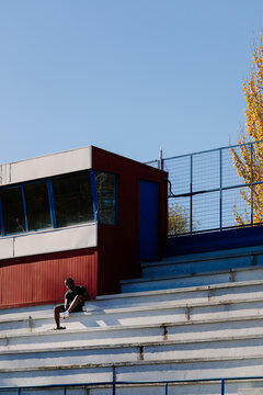 Athlete seated in the stands, switching his sneakers for his workout