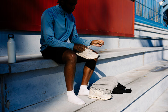 Athlete positioned in the bleachers fastening the laces on his shoes