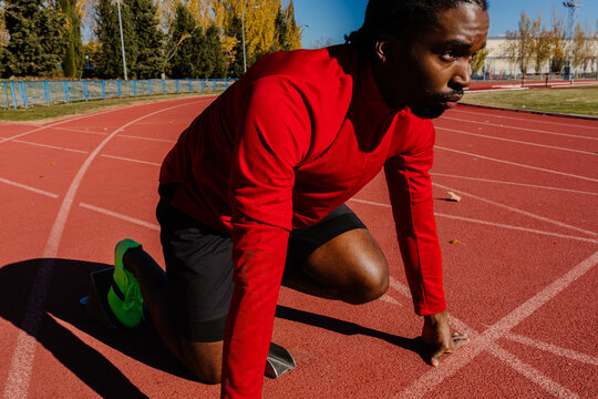 Sprinter aligning his feet in the starting blocks on the track