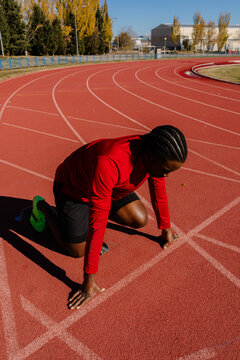 Sprinter arranging his feet on the starting blocks along the track