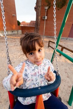 Young girl making funny face on playground swing