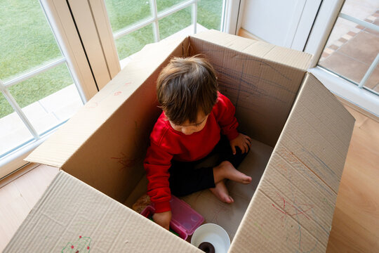 Toddler playing inside cardboard box using imagination at home