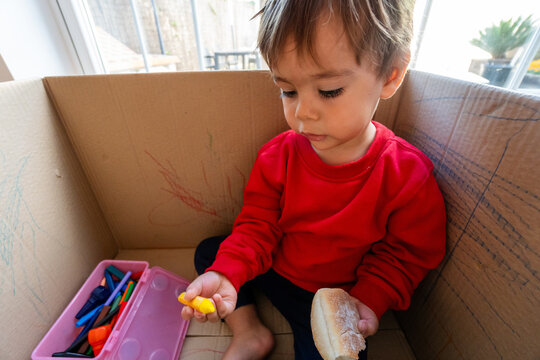 Toddler boy playing and drawing in cardboard box