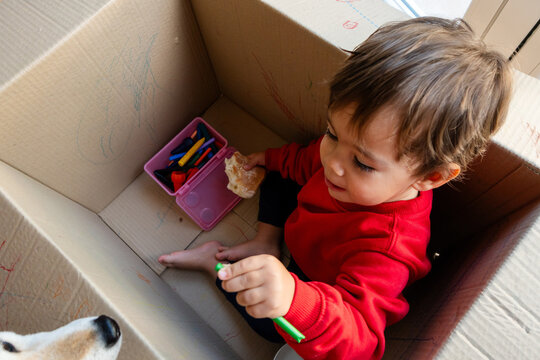 Toddler boy drawing inside cardboard box creating art