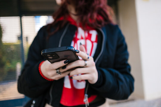 Anonymous red-haired woman sending text messages on her mobile phone.