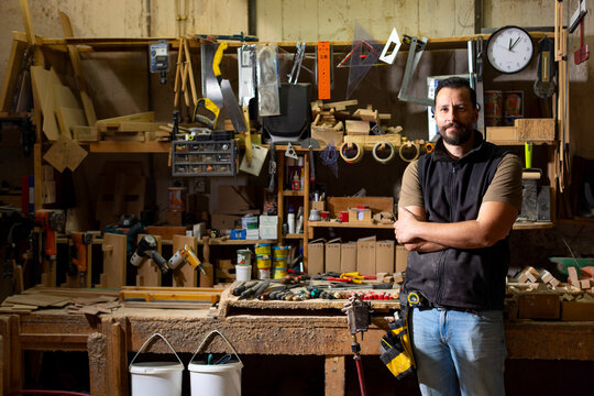 Woodworker stands in workshop with tools and materials around