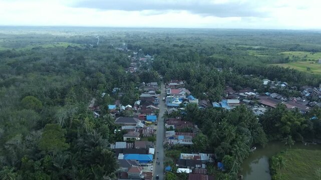 Aerial view of a rural village surrounded by rice fields captured by a drone. The image shows village houses, green paddy fields, and agricultural land, representing countryside life and farming activ