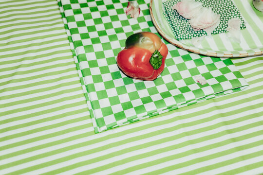 Green checkered table with a red pepper