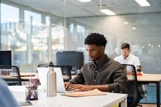 Young man using laptop working in modern office